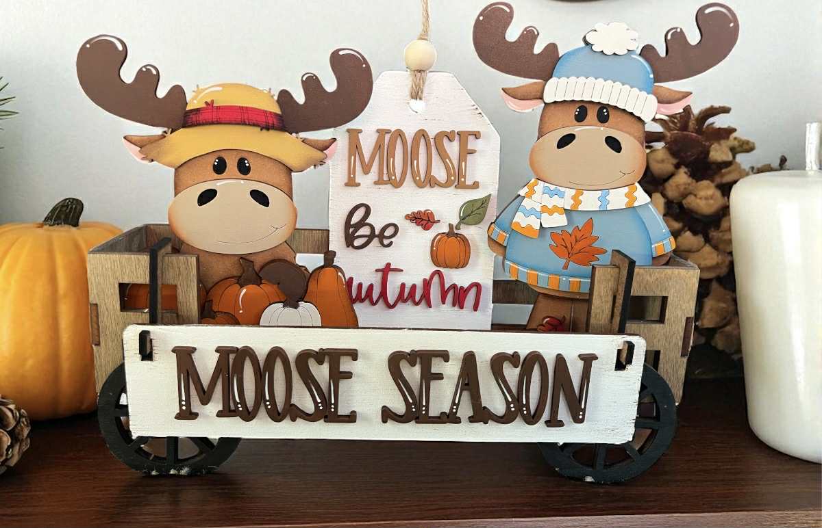 Decorative items with moose theme including a sign that reads 'Moose Season' on a wooden surface.