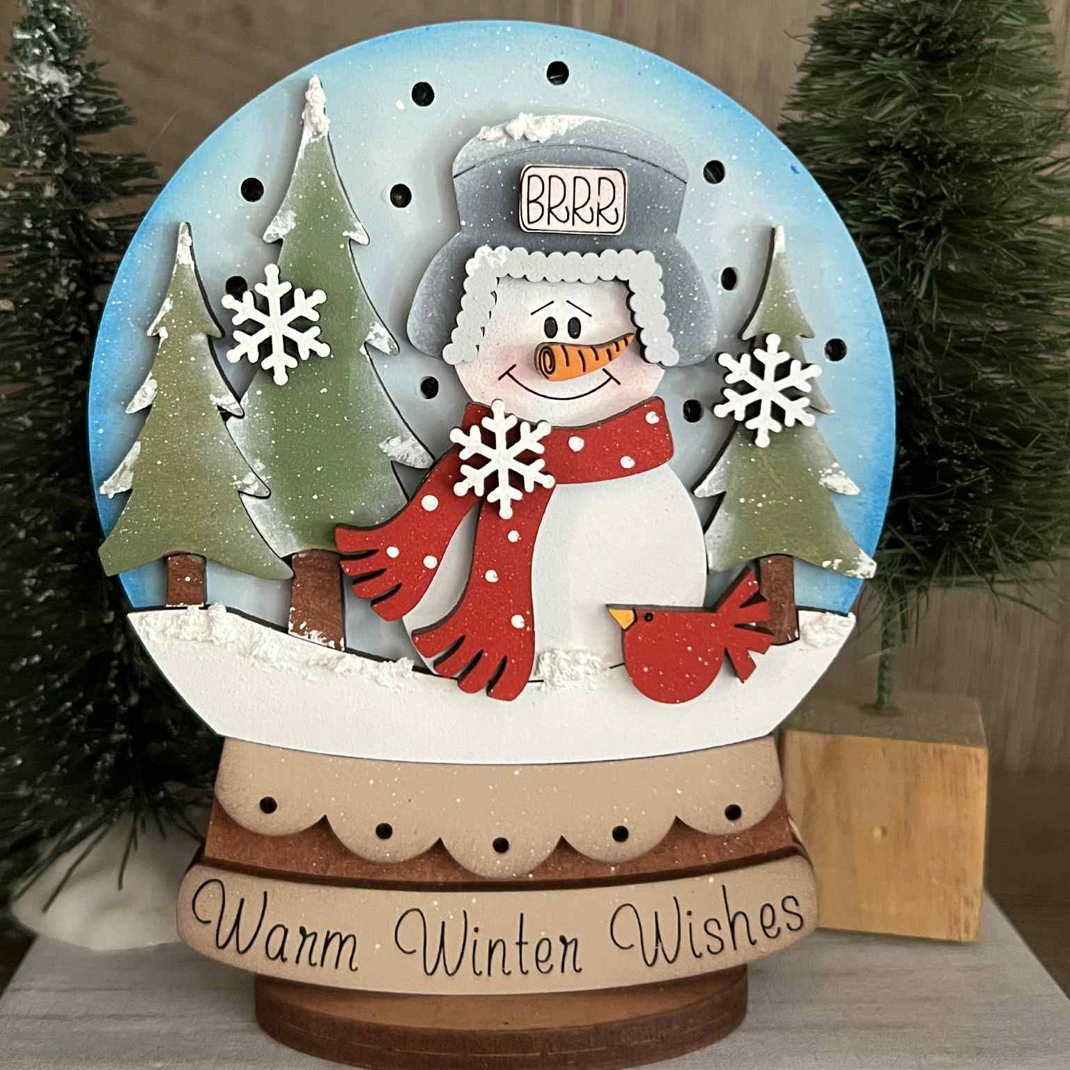 Decorative lighted snow globe with a snowman and winter scene on a wooden surface.