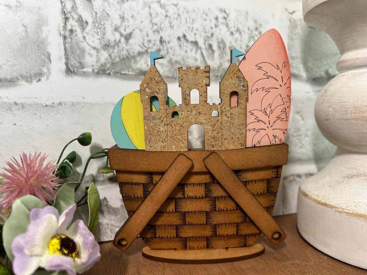 A decorative basket insert featuring a beach and summer theme with a sandcastle, surfboard, and palm trees 