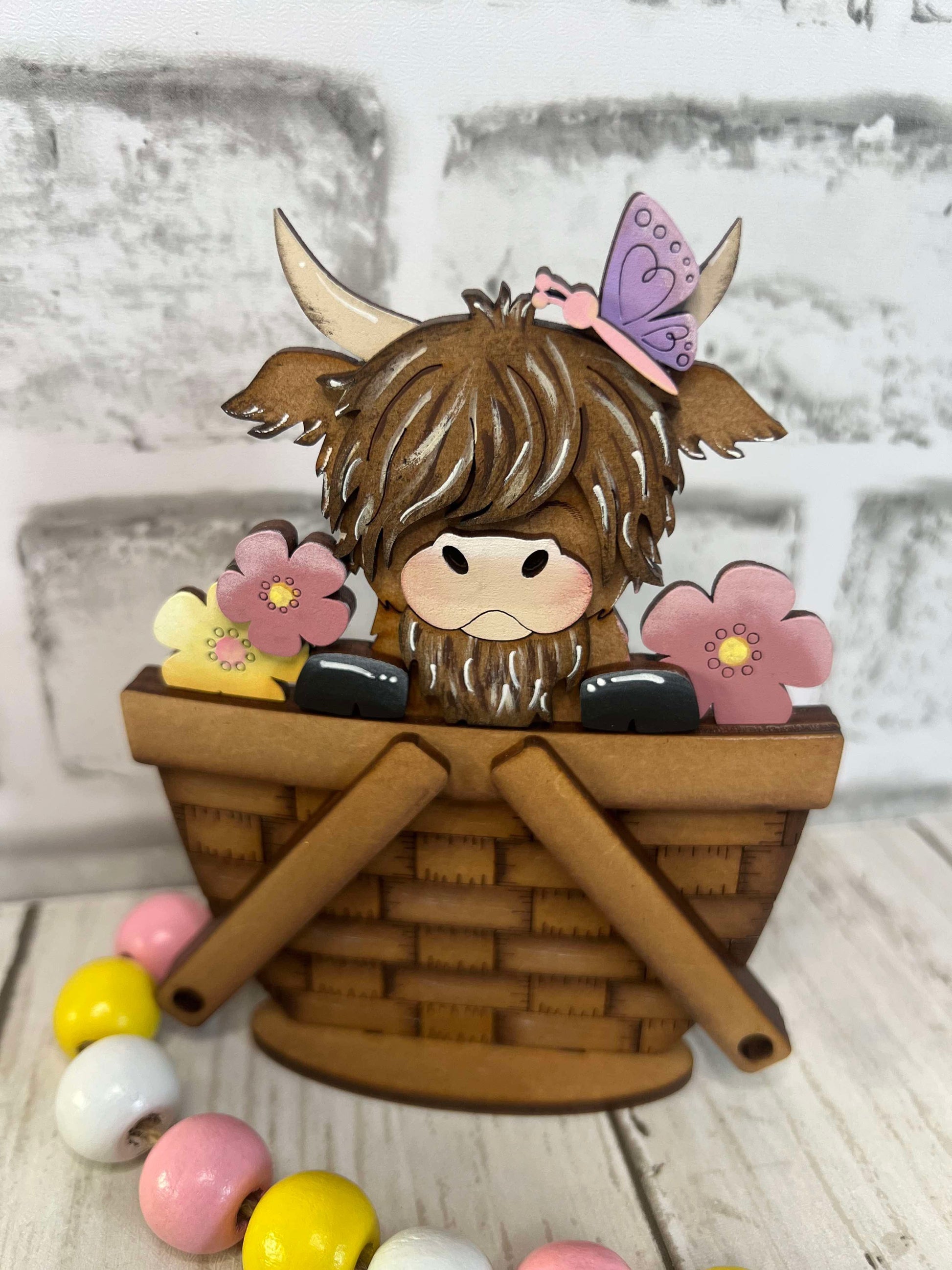 A decorative basket insert featuring a highland cow with flowers and a butterfly, designed for spring-themed decor.